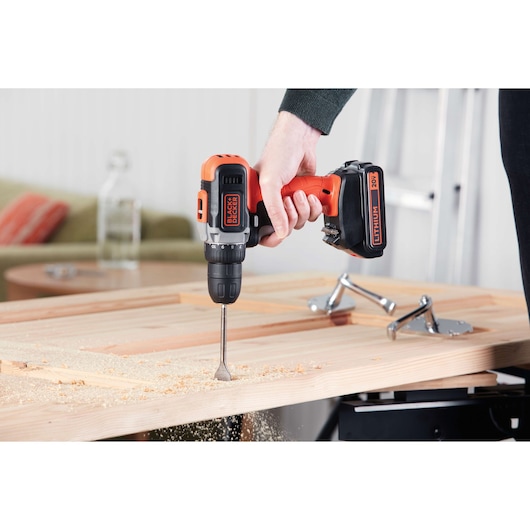 BLACKDECKER BCD703C1 cordless drill in use drilling into a wooden board, close-up angle.