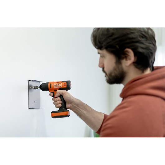 BLACKDECKER BCD712VHD cordless drill used to install a metal plate on a white wall.