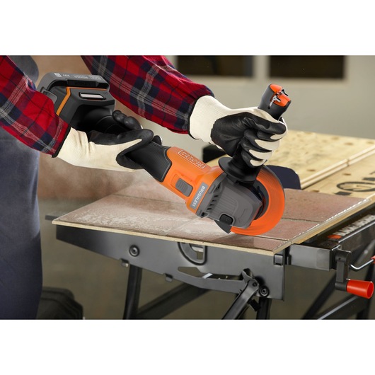Photo of BLACKDECKER BCG6L8B cordless angle grinder with orange accents cutting tile on a workbench.