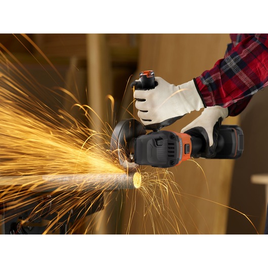 Photo of BLACKDECKER BCG6L8B angle grinder cutting metal pipe, sparks flying, worker wearing gloves.