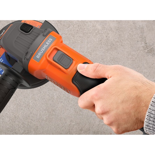 Photo of a hand holding a BLACK+DECKER BCG6L8B brushless angle grinder, focusing on the power switch and handle.