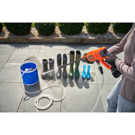 BLACKDECKER BCPC20D1 portable pressure washer cleaning boots, person holding washer, outdoor patio scene.