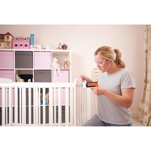BLACKDECKER BCRTA601I cordless screwdriver used by a woman assembling a white crib in a nursery.