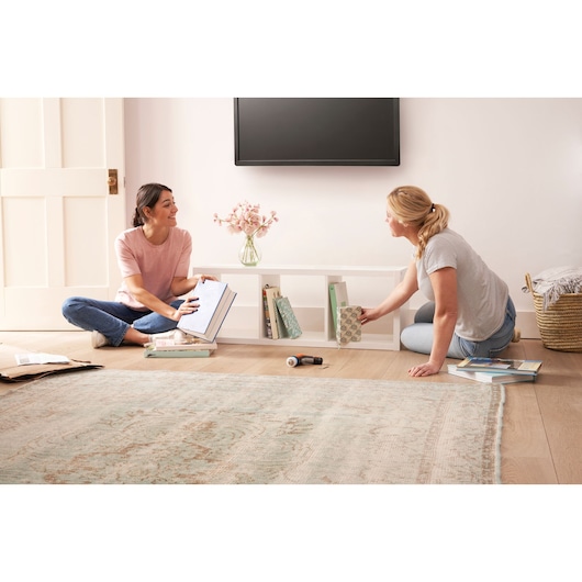 BLACKDECKER BCRTA601I cordless screwdriver on floor with two people organizing books in living room.