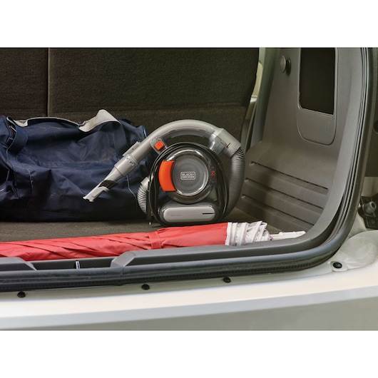 BLACK+DECKER BDCV560F-LA portable car vacuum with hose attachment, placed in a vehicle trunk next to a red umbrella.