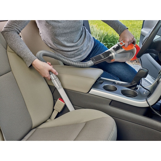 BLACKDECKER BDCV610-LA handheld vacuum cleaning car seat area with flexible hose attachment.