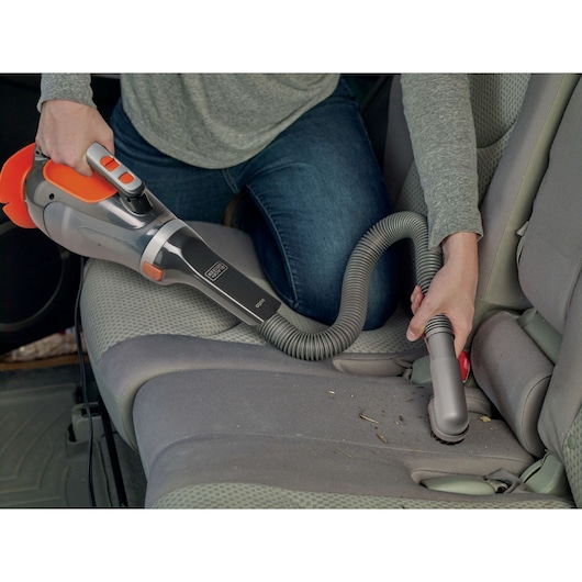 Photo of BLACKDECKER BDCV610-LA handheld vacuum with hose cleaning car seat upholstery.