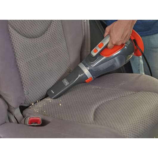 BLACKDECKER BDCV610-LA handheld vacuum cleaner used to clean crumbs from a gray car seat.