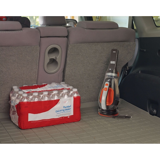 BLACK+DECKER BDCV610-LA handheld car vacuum with cord, black and orange, shown upright in vehicle trunk.