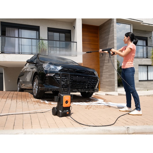 BLACKDECKER BEPW1520L pressure washer cleaning a black car in a residential driveway.
