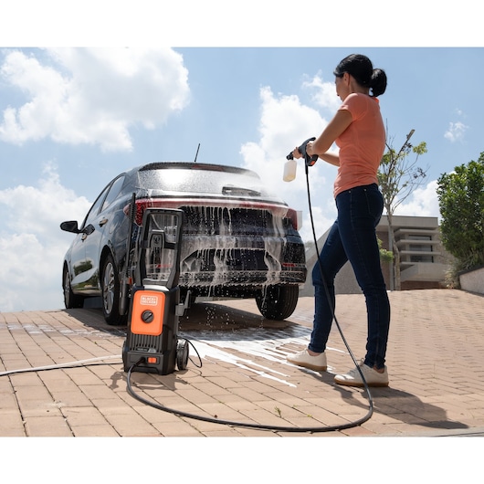 Photo of BLACKDECKER BEPW1520L pressure washer cleaning a black car outdoors with foam spray.