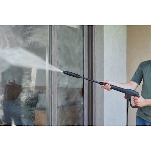 BLACKDECKER BEPW1600H pressure washer spraying water on glass door, side view, product in use.