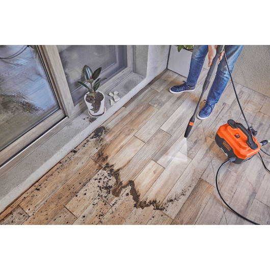 BLACKDECKER BEPW1600H pressure washer cleaning dirt from outdoor tile floor, side angle.
