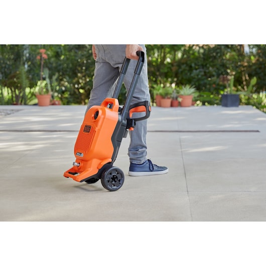 BLACKDECKER BEPW1800T portable orange pressure washer on wheels being pulled outdoors.