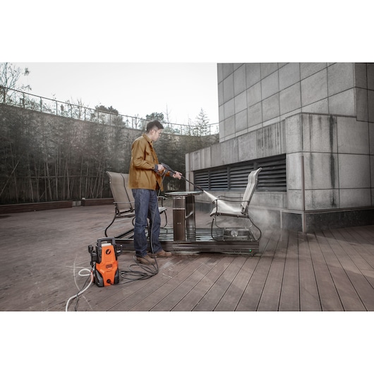 Photo of BLACKDECKER BEPWB1740 pressure washer cleaning outdoor furniture on a wooden deck.