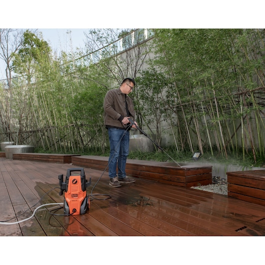 Photo of BLACKDECKER BEPWB1740 pressure washer cleaning outdoor wood deck with person spraying water.