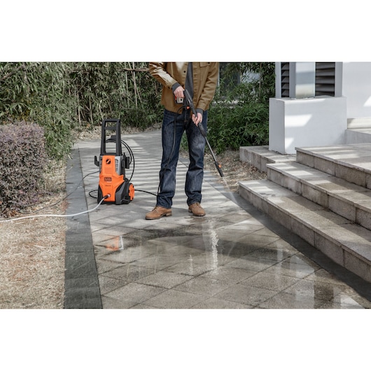 Photo of BLACKDECKER BEPWB2000 pressure washer cleaning outdoor tiled path near stairs, person using the spray wand.