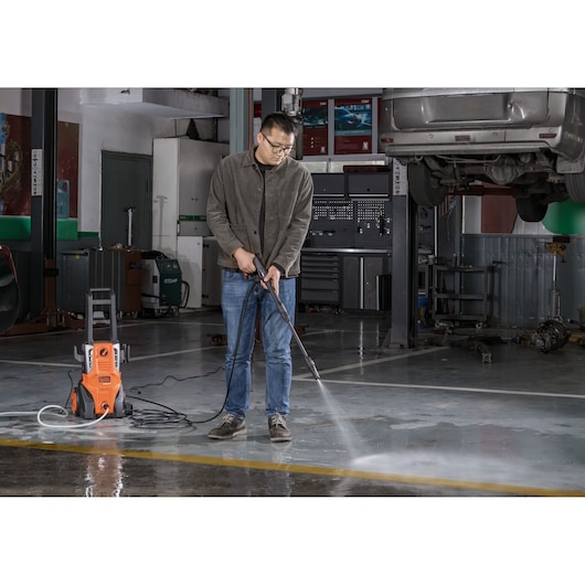 Photo of BLACKDECKER BEPWB2000 pressure washer in use cleaning a garage floor, person operating unit.