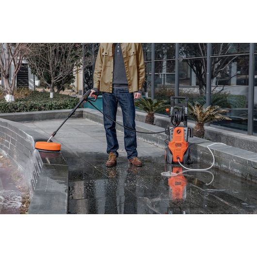 BLACKDECKER BEPWB2400 pressure washer being used to clean outdoor pavement with surface attachment.