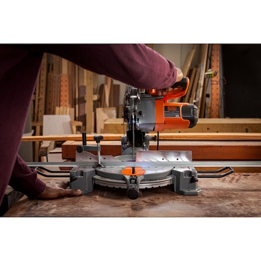 BLACKDECKER BES7101800MS miter saw in use on a woodwork table, orange and gray color, front angle.