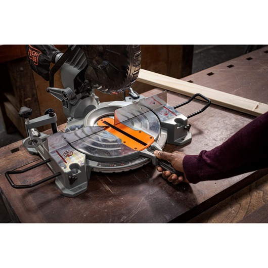 BLACKDECKER BES7101800MS miter saw on workbench, side angle, person adjusting handle.