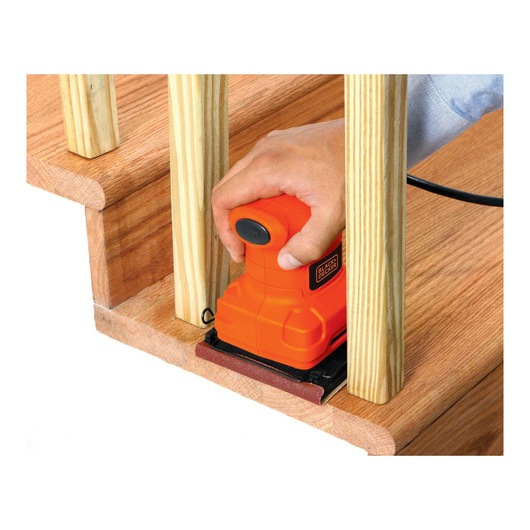 BLACKDECKER BS200 orange hand sander sanding wooden staircase, close up view.