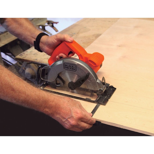 Photo of BLACKDECKER CS1004 circular saw cutting plywood, orange handle, user holding tool against work surface.