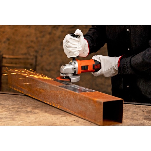 BLACKDECKER G720X angle grinder in use, sparks flying from grinding rusty steel pipe.