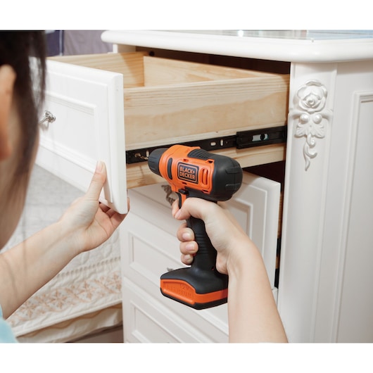 Photo of BLACKDECKER LD12S cordless drill being used to repair a white cabinet drawer.