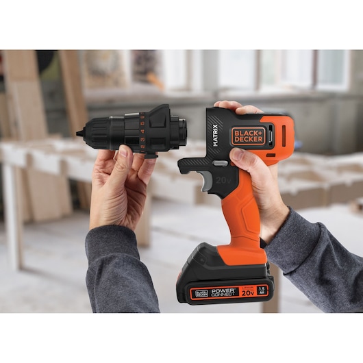 BLACK+DECKER MTX20K3B cordless drill with orange and black body, 20V battery, and detachable chuck held in hands.
