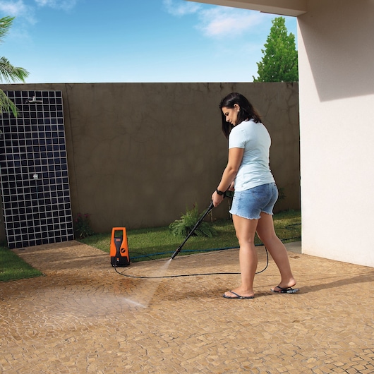 BLACKDECKER PW1450TD pressure washer cleaning patio tiles outdoors.