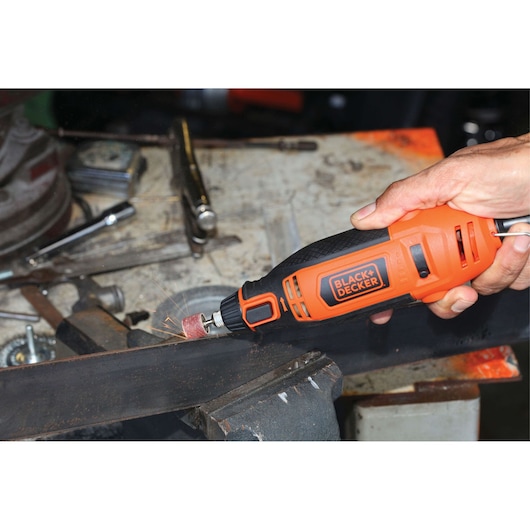 Photo of BLACK+DECKER RT18KA rotary tool sanding metal in workshop setting.
